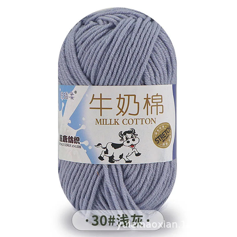 A ball of gray milk cotton blend yarn with a label showing the name and thread count.