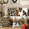 A collection of leopard print decorative pillows and a red gift box on a wooden surface.