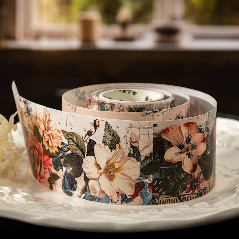 Roll of vintage botanical washi tape featuring floral designs in muted pinks, greens, and creams.
