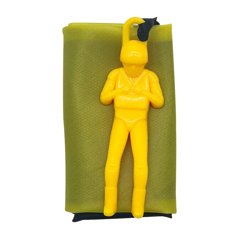 A yellow hand-throw parachute toy with a black mini soldier, displayed against a olive green fabric background.