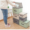 A person is placing a white item into a stack of light green and gray fabric storage boxes.