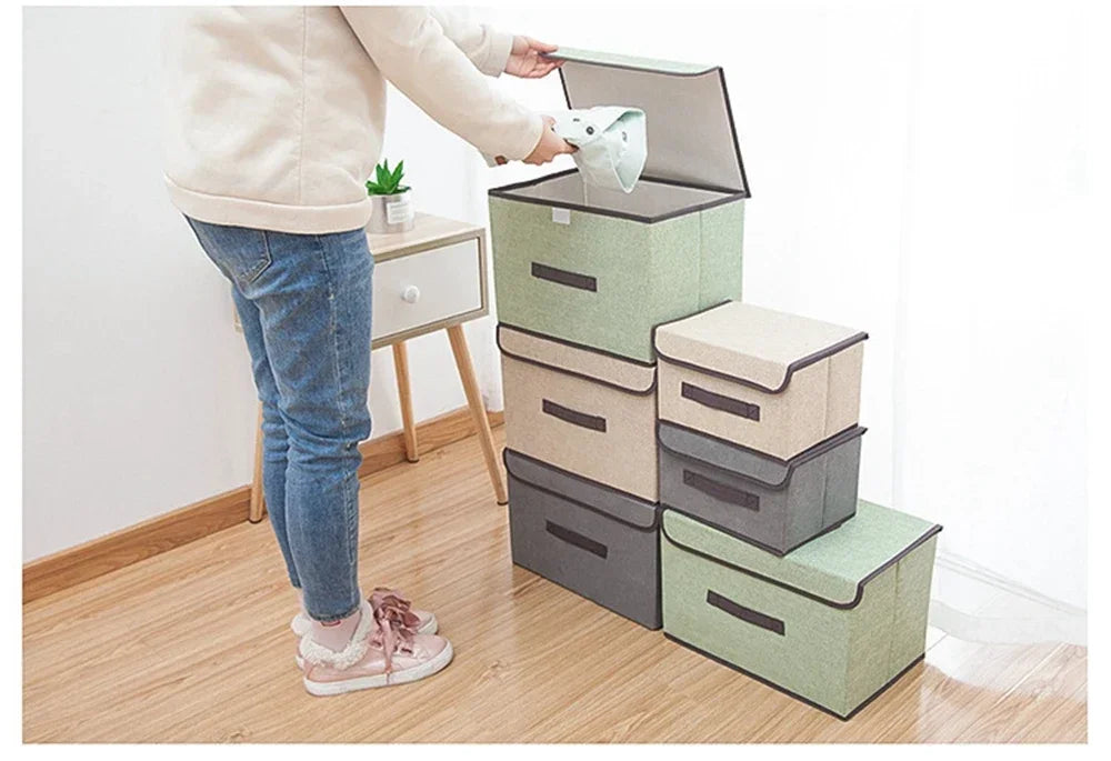 A person is placing a white item into a stack of light green and gray fabric storage boxes.