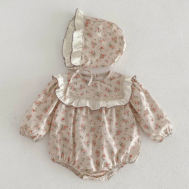 A light floral cotton romper for a baby girl featuring lace trim and gathered details.