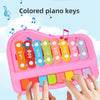 A hand is playing colored piano keys on a pink xylophone for toddlers.