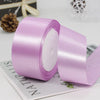 A roll of light purple satin ribbon used for gift wrapping and crafts, shown on a white surface.