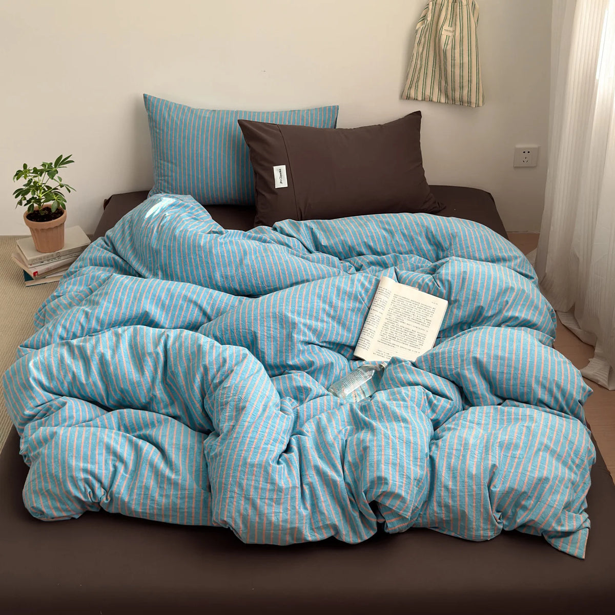 A blue and white striped duvet cover set with a dark brown pillow on a bed.