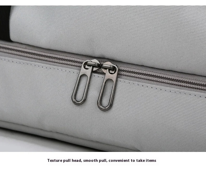 Close-up of a gray fabric travel duffle bag with a silver texture pull head and zipper.