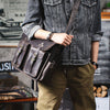 Eine Person trägt eine Jeansjacke und hält eine braune, vintage, echte Ledermappe für Laptops.