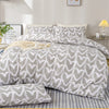 A heart print duvet cover set with pillowcases in soft gray and white patterns on a bed.