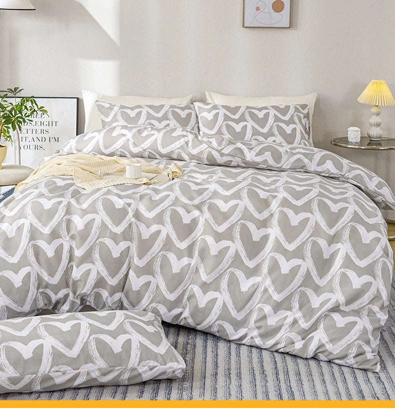 A heart print duvet cover set with pillowcases in soft gray and white patterns on a bed.