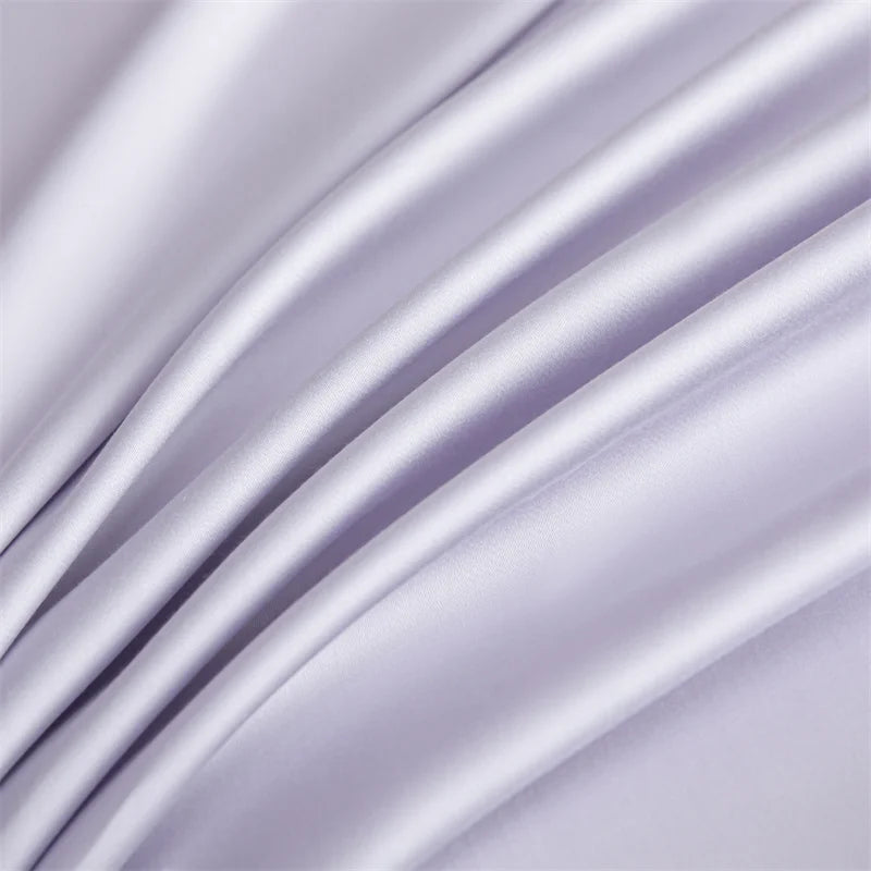 A close-up of a silky soft, light purple bamboo flat sheet draped in flowing folds.