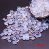 Clear and blue opalite crystal stone chips scattered on a dark surface.