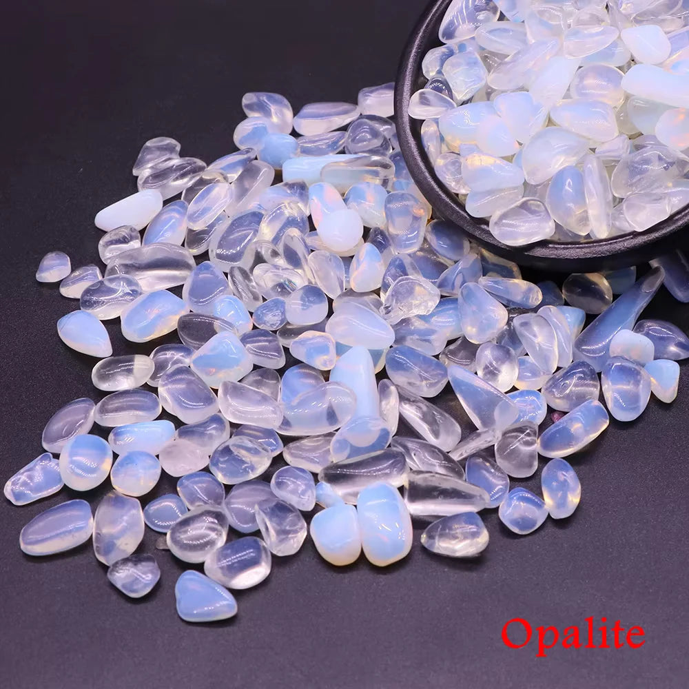 Clear and blue opalite crystal stone chips scattered on a dark surface.