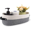 A woven cotton rope storage basket holding a roll of toilet paper and a small floral arrangement.