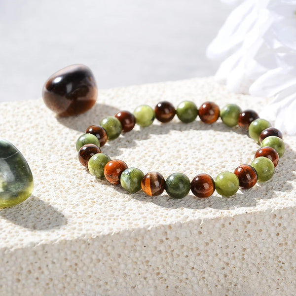 Set aus natürlichen Tigerauge-Perlen und einem Armband auf einer hellen Oberfläche mit weißen Blumen.