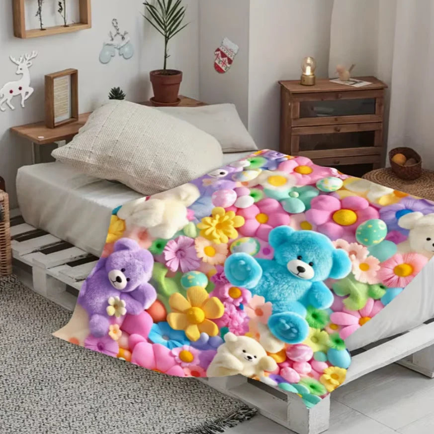 A colorful flannel throw blanket featuring various pastel-colored floral patterns and teddy bear motifs draped over a white b