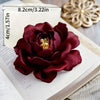 A deep burgundy 3D rose silicone mold for crafts rests on an open book with measurement markings.