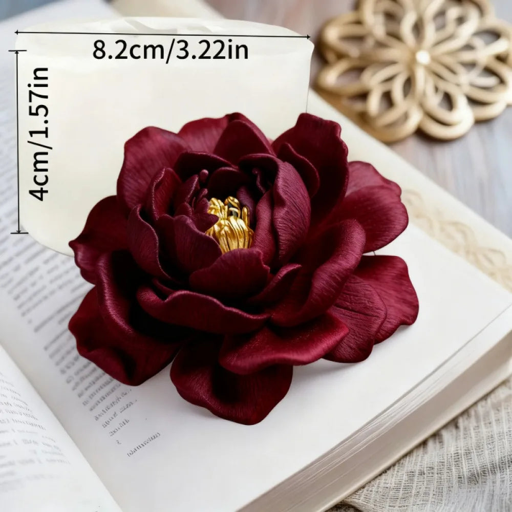 A deep burgundy 3D rose silicone mold for crafts rests on an open book with measurement markings.
