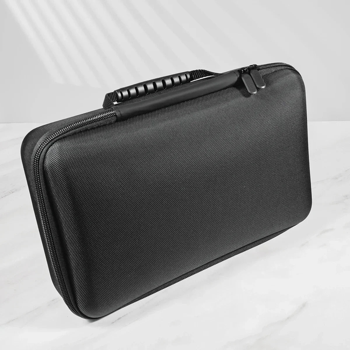 A black portable leather watch travel case with a zippered closure is shown on a white marble surface.