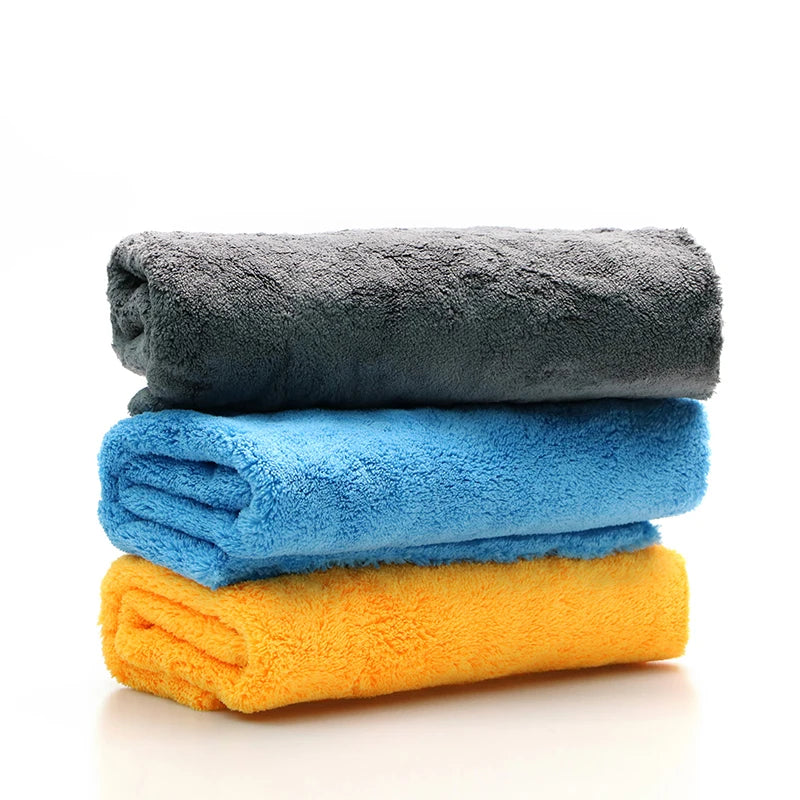 A stack of three brightly colored microfiber cleaning cloths: gray, blue, and yellow.
