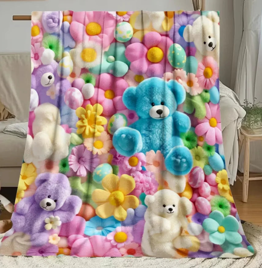 A colorful flannel throw blanket featuring various pastel-colored teddy bears and floral patterns.