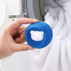 A hand holds a blue laundry ball with a white insert, used for pet hair removal.
