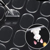 A close-up view of a white mouse patch with black ears and paws resting on a dark surface.
