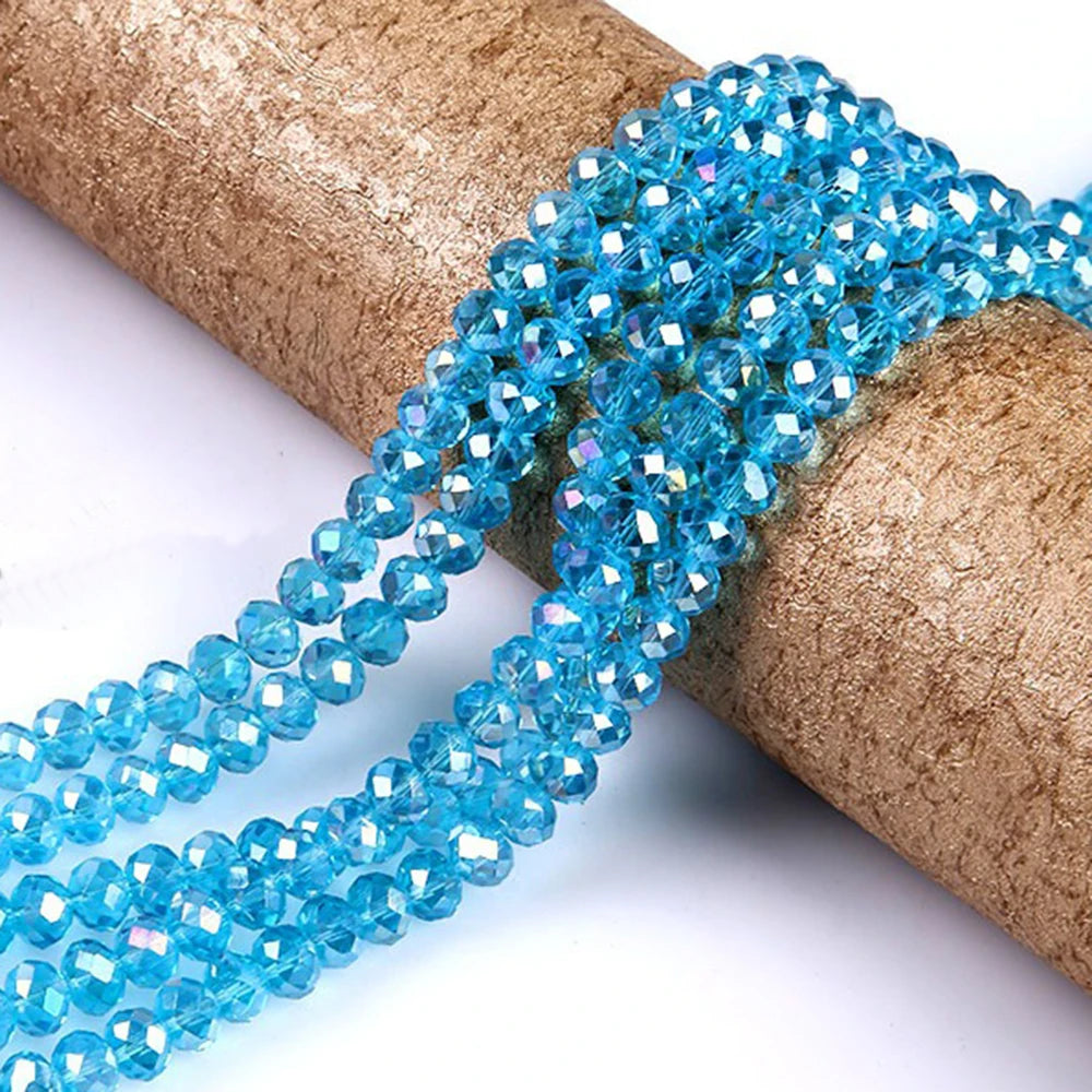 A strand of bright blue faceted crystal glass spacer beads is coiled on a brown cylindrical object.