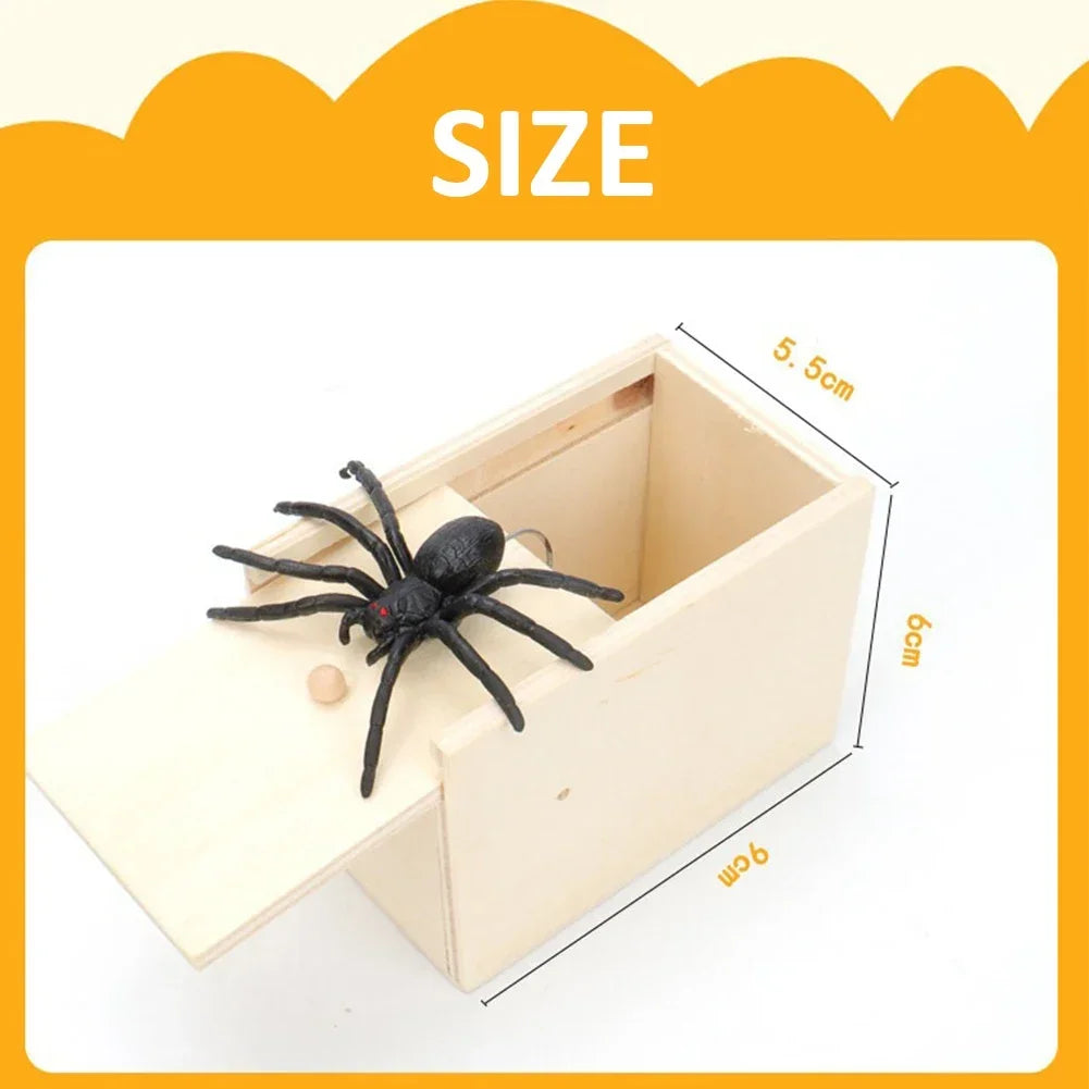 A wooden box with a pop-out feature is shown, containing a black spider toy.