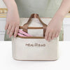 A person holds a beige insulated lunch bag with a brown strap and pink utensils on a white table.
