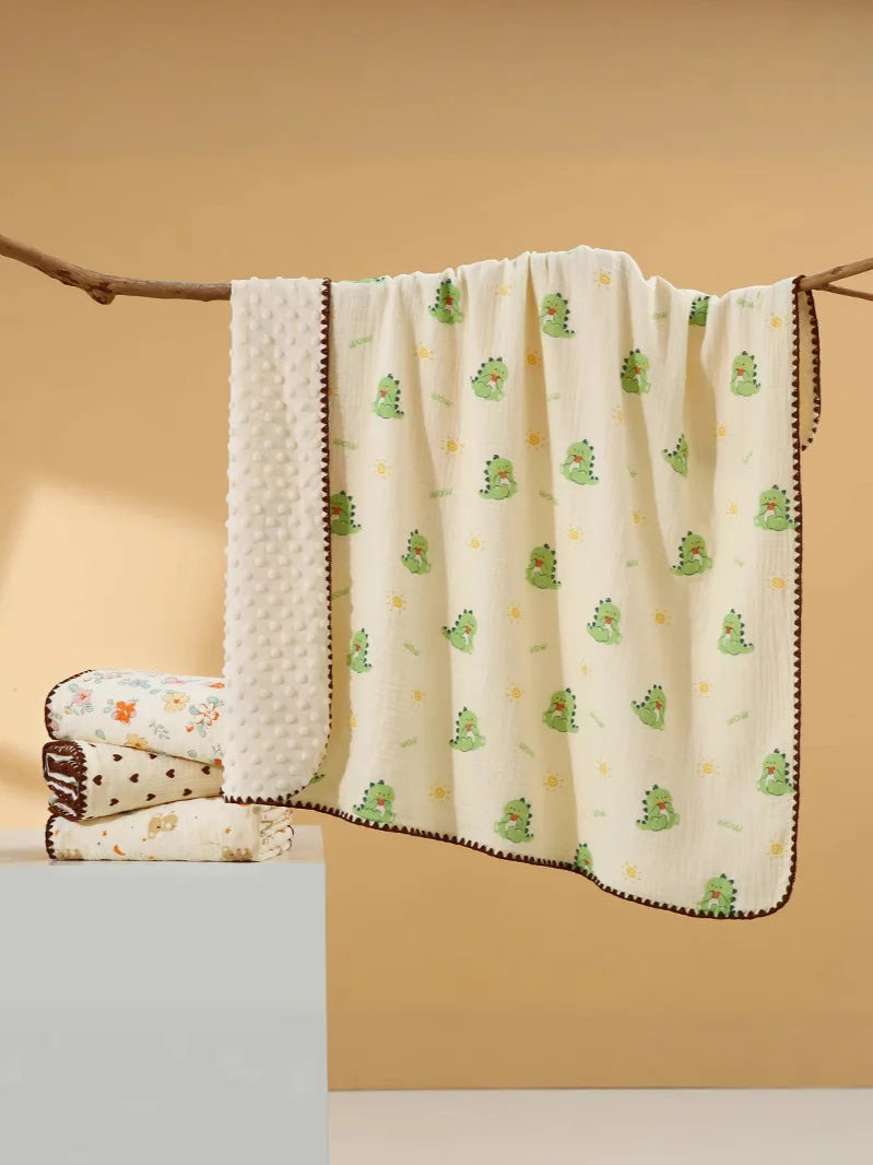 A cream-colored cotton gauze baby swaddle blanket with a bear print pattern is hanging on a wooden branch.
