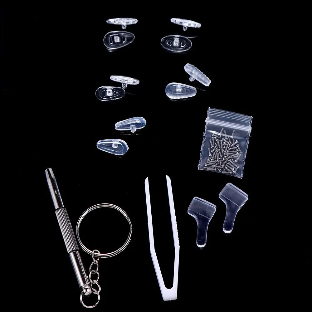 A collection of complete glasses repair kit components including nose pads, screws, and precision tools arranged on a black b