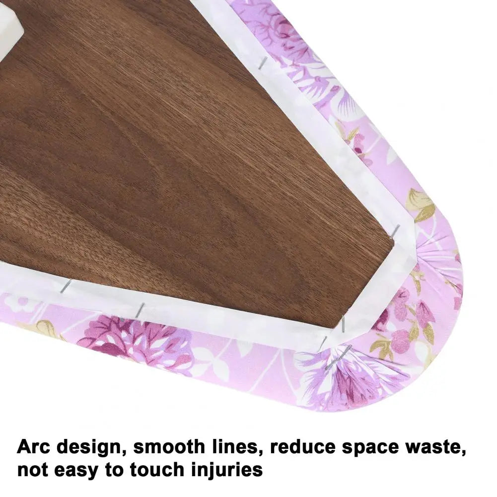 A close-up view of a wooden ironing board with a pink floral cover and white trim.