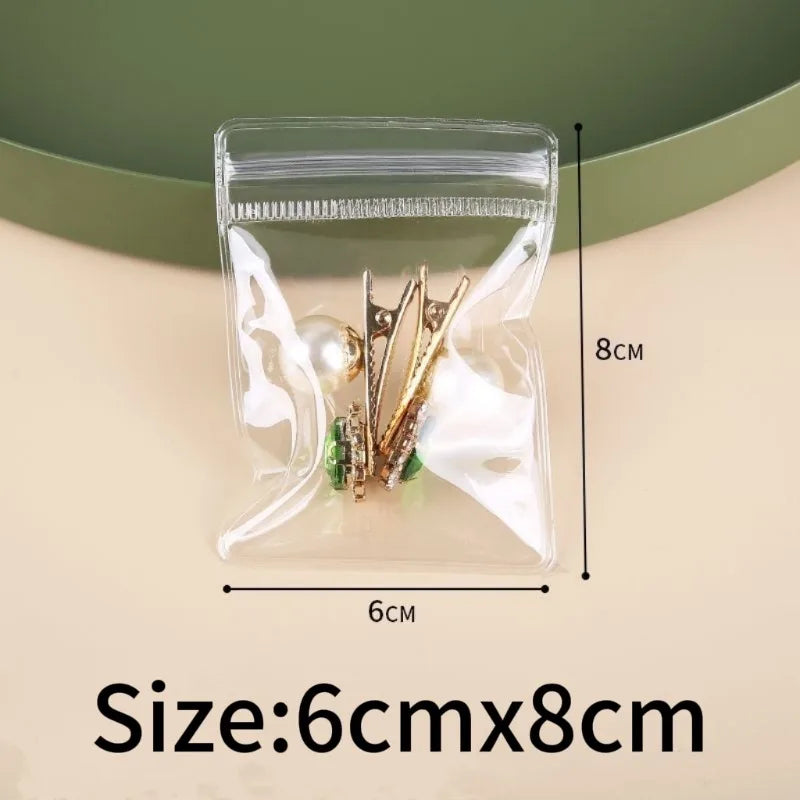 Clear self-sealing jewelry storage bag containing gold-toned earrings and other small jewelry items