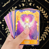 A hand holds a tarot oracle card showing the word YES with golden angelic imagery on a purple background.