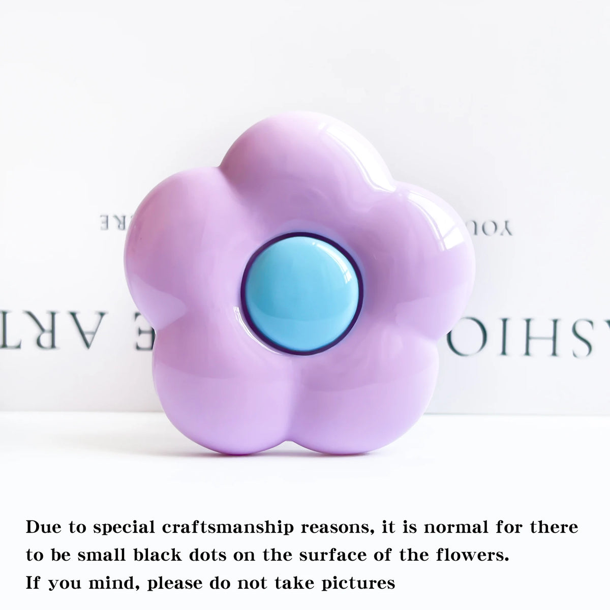 A light purple, flower-shaped silicone phone grip stand with small black dots on the surface.