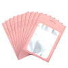 A stack of pink colorful mylar ziplock bags with clear windows for jewelry and small item packaging.