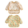 A light beige baby bib with a floral pattern and a yellow trim, featuring a waterproof long-sleeve design.