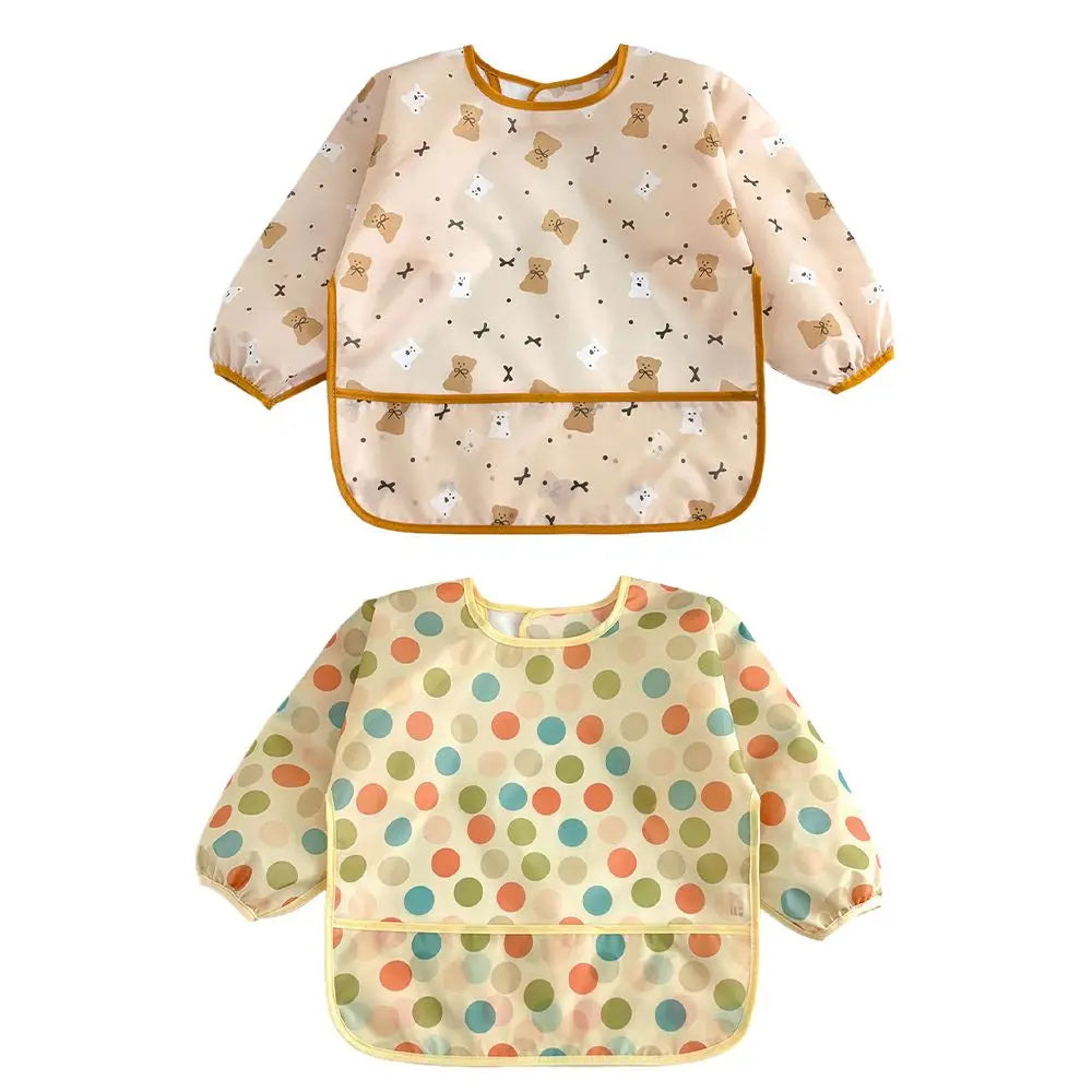 A light beige baby bib with a floral pattern and a yellow trim, featuring a waterproof long-sleeve design.