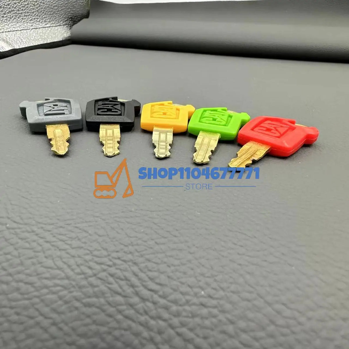 A set of five colored replacement ignition keys for Caterpillar excavators, including black, gray, yellow, green, and red.