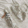A white lace double-layer folding umbrella with a light pink handle is shown on a white fabric background.