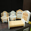 A miniature dollhouse furniture set featuring a light wood and white color palette including a bed, chairs, and cabinet.