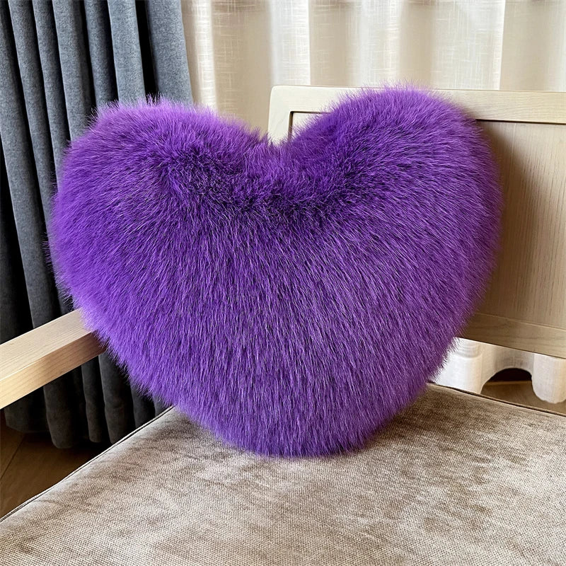 A vibrant purple plush heart-shaped throw pillow resting on a light wooden surface.