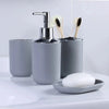 A silver soap dispenser and brush holder set with a white bar of soap on a white countertop.