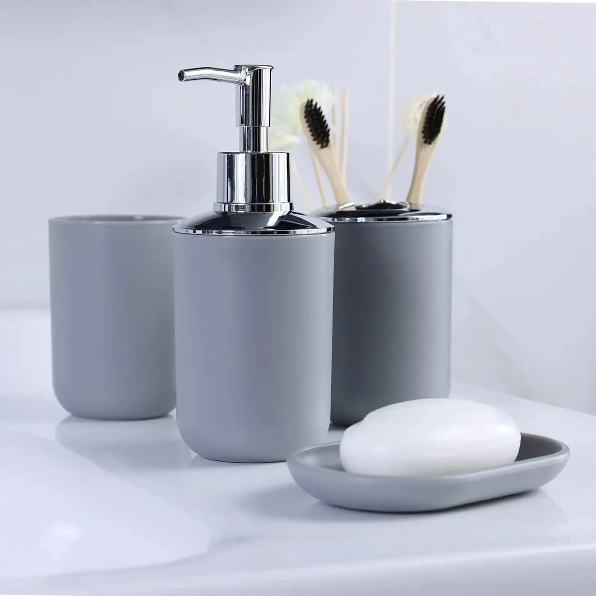 A silver soap dispenser and brush holder set with a white bar of soap on a white countertop.