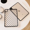 A light-colored iPad is shown alongside its black polka dot protective case on a white surface.