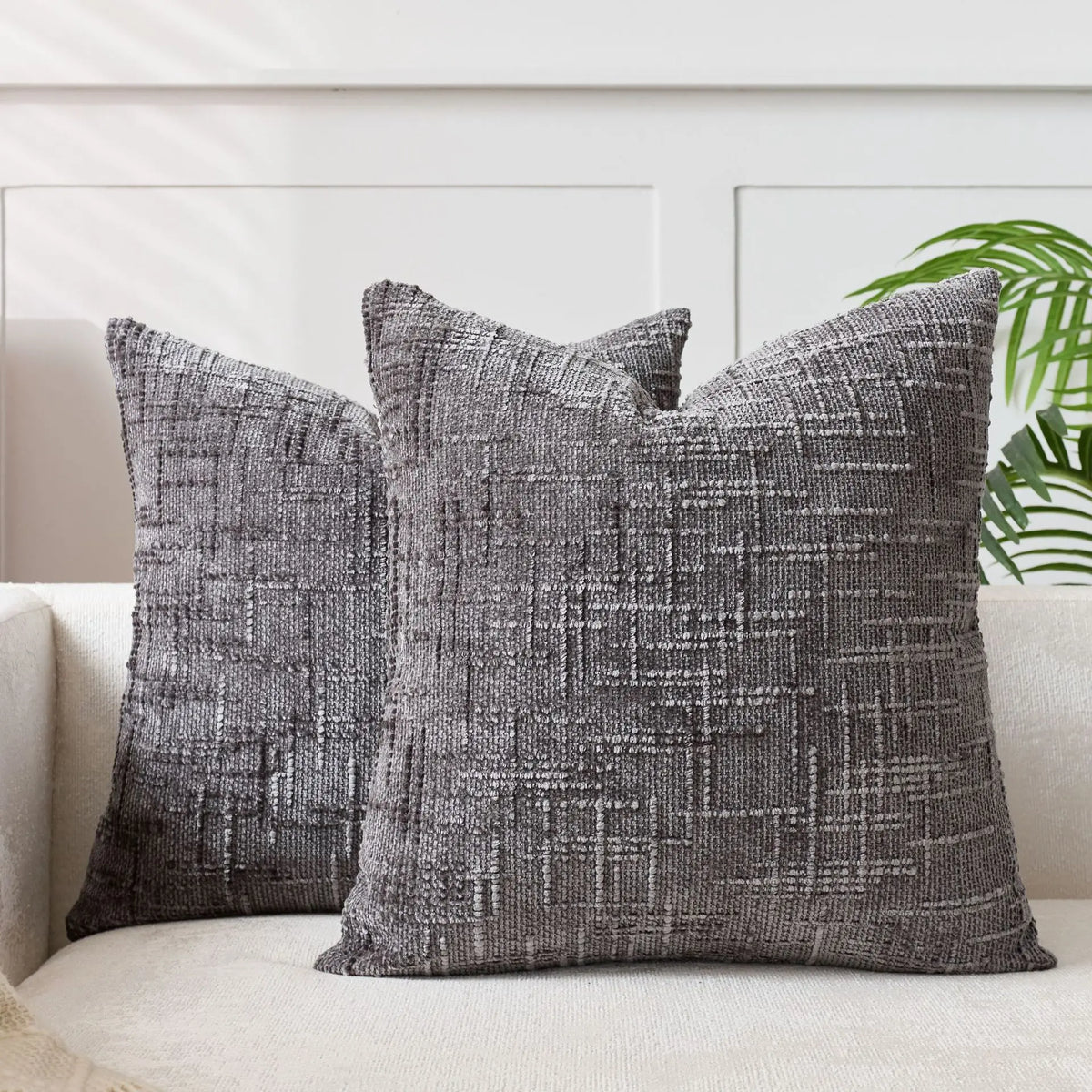 A dark gray handwoven chenille texture cushion cover resting on a light-colored sofa.