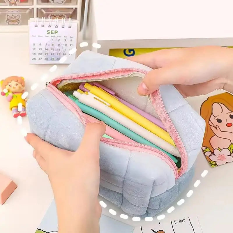 A hand is opening a light blue portable makeup bag filled with various pens and pencils.