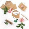Kraft paper envelopes with pink roses and greenery, including a thank you note.