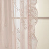 Sheer pink and white ruffled French lace curtains with floral embroidery hanging in a window.